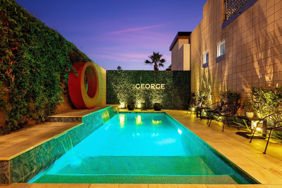 A private resort-style pool framed by lush greenery and warm architectural walls, glowing at dusk. Featuring a tranquil waterfall edge and ambient lighting, this intimate oasis is designed for elevated relaxation and unforgettable evenings.