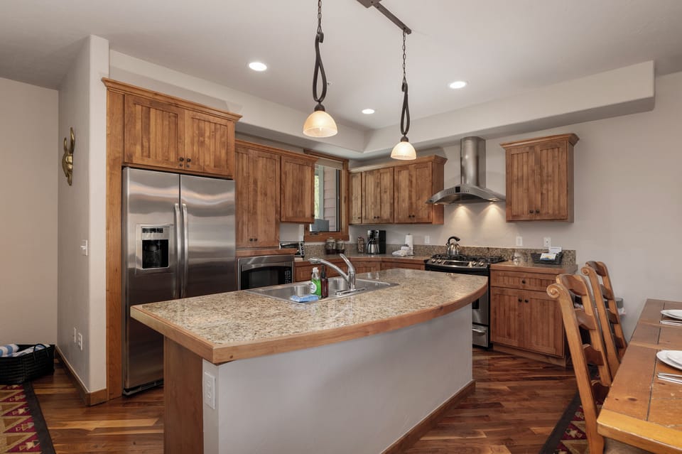 - Fully equipped kitchen with granite island, pendant lighting, and stainless appliances - Rich wood cabinetry and curved countertop create a warm, lodge style feel - Ideal for home cooked meals, morning coffee, or gathering around together