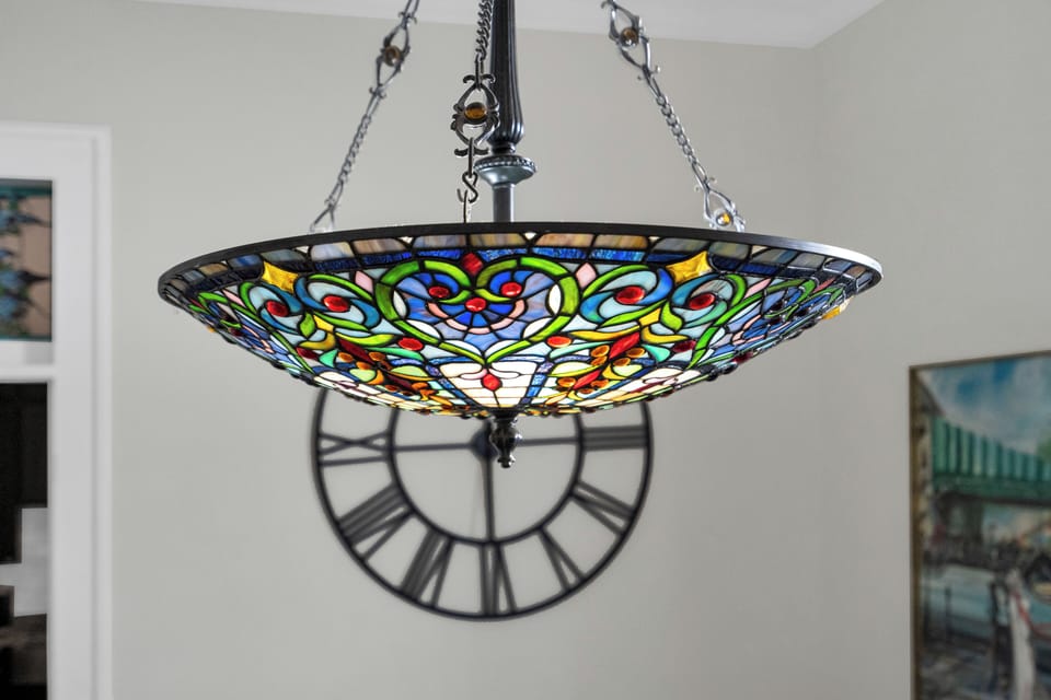 Stained-glass chandelier casting warm, colorful light — a stunning centerpiece.
