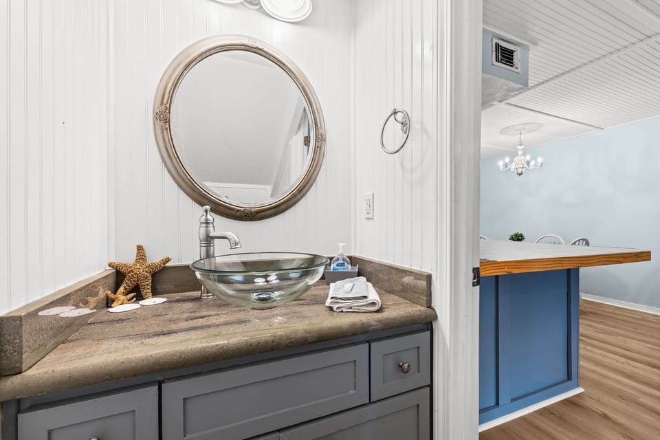Downstairs half bath with vessel sink and coastal mirror.