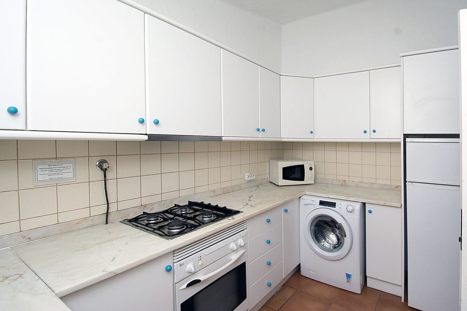 The bright kitchen is equipped with a gas hob, oven, microwave, washing machine, fridge and freezer.