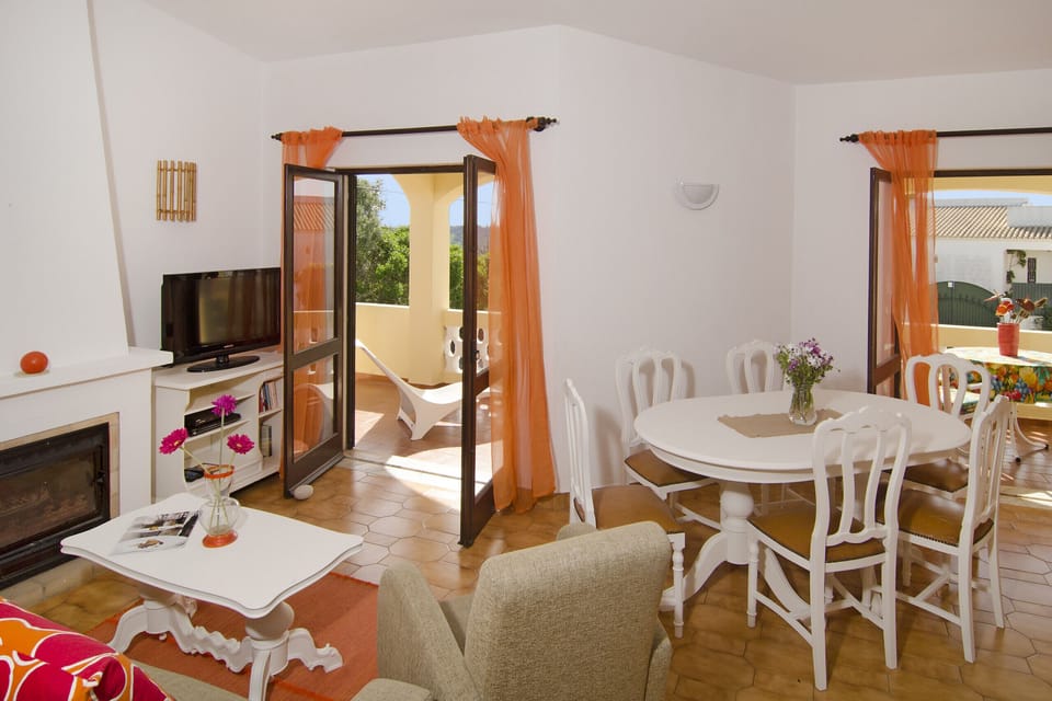 Villa Beatriz: Living room with fireplace and TV in the sitting area consisting of sofa and armchair. There is also a white wooden dining table for six people.