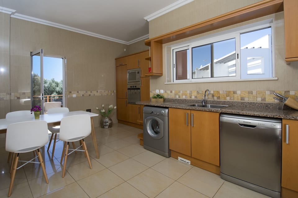 The large kitchen in Quinta Marina is well equipped. There is an oven, a microwave, a dishwasher and also a washing machine. Opposite the kitchenette is a small dining table and through the glass door you can access the terrace with the lounge furniture and barbecue.
