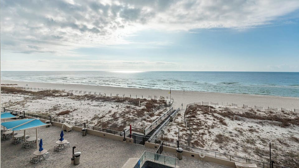 Enjoy the outdoor seating area with umbrellas, perfect for relaxing while taking in the tranquil beach views