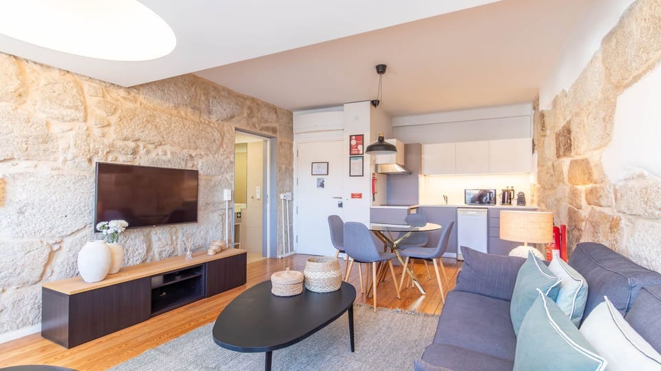 Imagine relaxing on the comfy sofa after a day of exploring, enjoying your favorite shows on the wall-mounted TV, or preparing a quick meal in the compact, well-appointed kitchen. The unique exposed stone wall adds a touch of historic charm to this modern