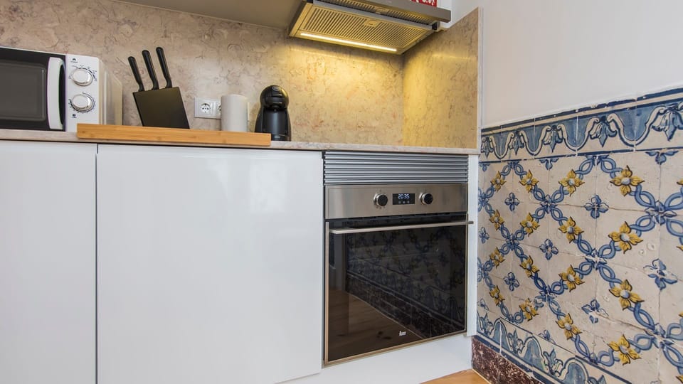 This compact, fully equipped kitchen with charming traditional Portuguese tiles invites you to prepare delicious meals with ease, featuring modern appliances nestled amongst classic design. Enjoy the convenience of home cooking, from a quick coffee to a f
