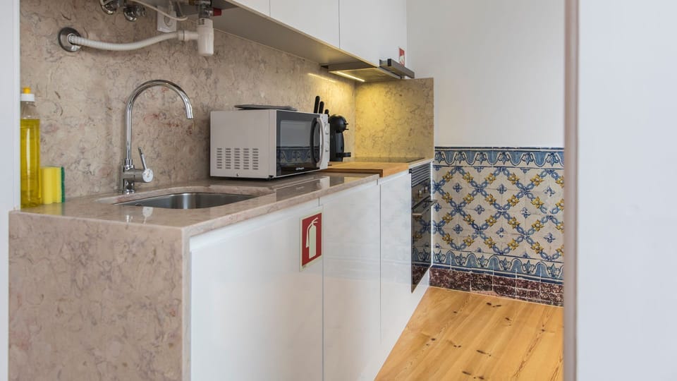 Experience the ease of preparing meals in this bright, compact kitchen featuring traditional Portuguese tiles and modern appliances, perfect for a quick breakfast or a gourmet dinner.