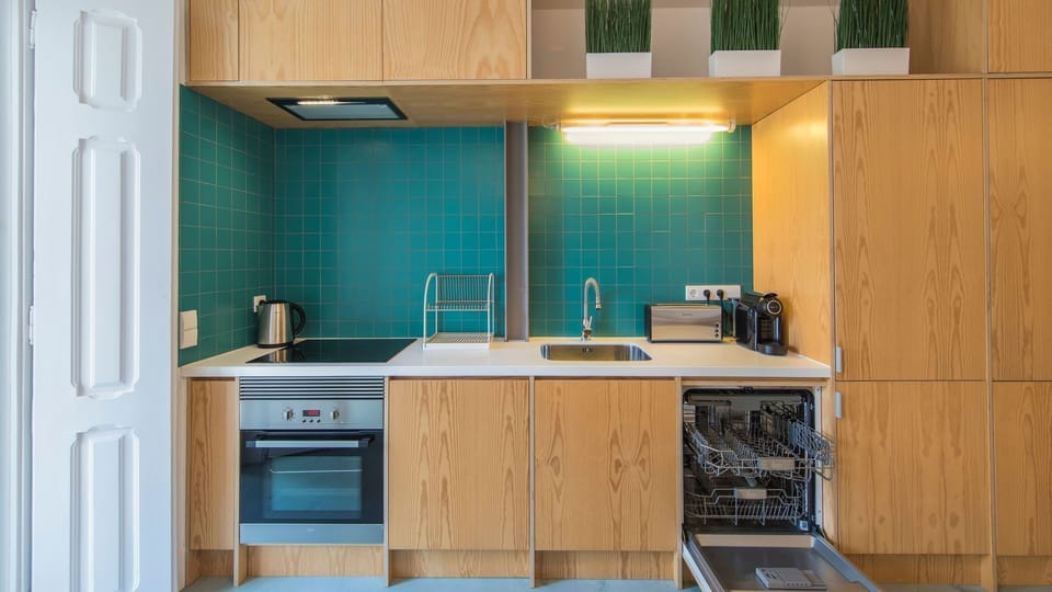 Prepare delicious meals in this fully-equipped kitchen, featuring sleek wooden cabinetry, modern appliances, and vibrant teal tiling. Everything you need for a gourmet experience, right at your fingertips.