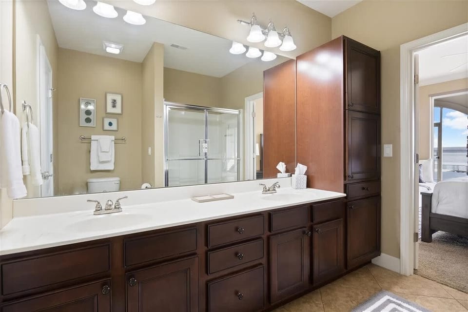 Bright full bathroom featuring an expansive vanity, double-sink setup, generous counter space, and ample storage for added guest convenience.