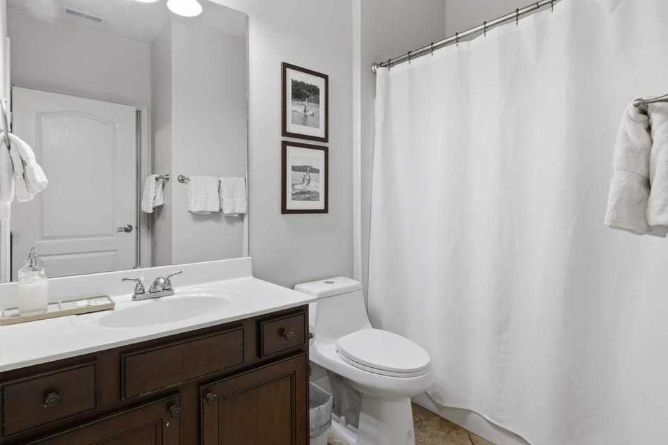 Clean and comfortable full bathroom featuring a spacious vanity, modern fixtures, large mirror, and a convenient tub and shower combination.