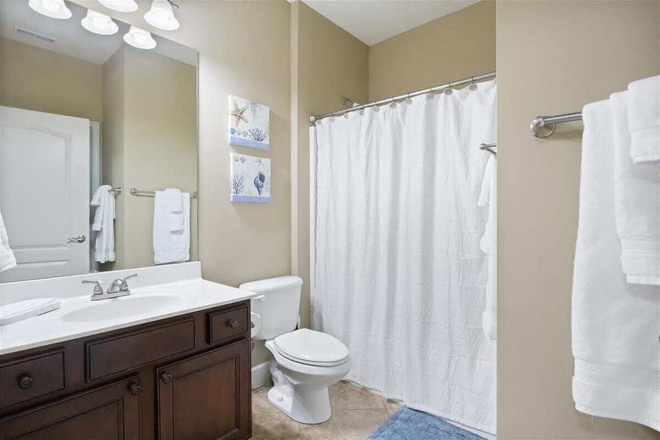 Clean and comfortable bathroom featuring a spacious vanity, modern fixtures, bathtub and shower combination, and plenty of counter space for guests.