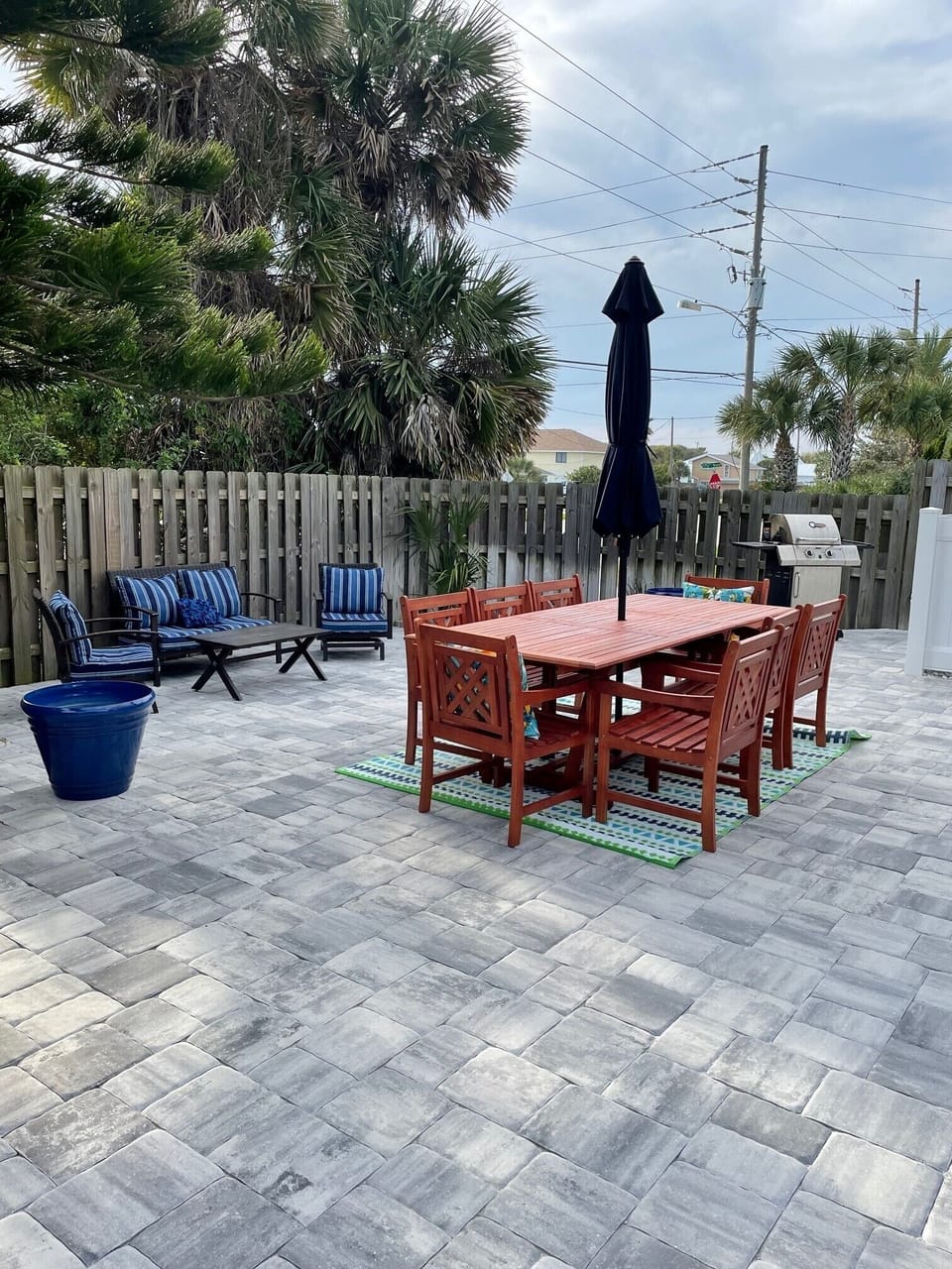 Large fenced in patio area with grill, dining table and seating area