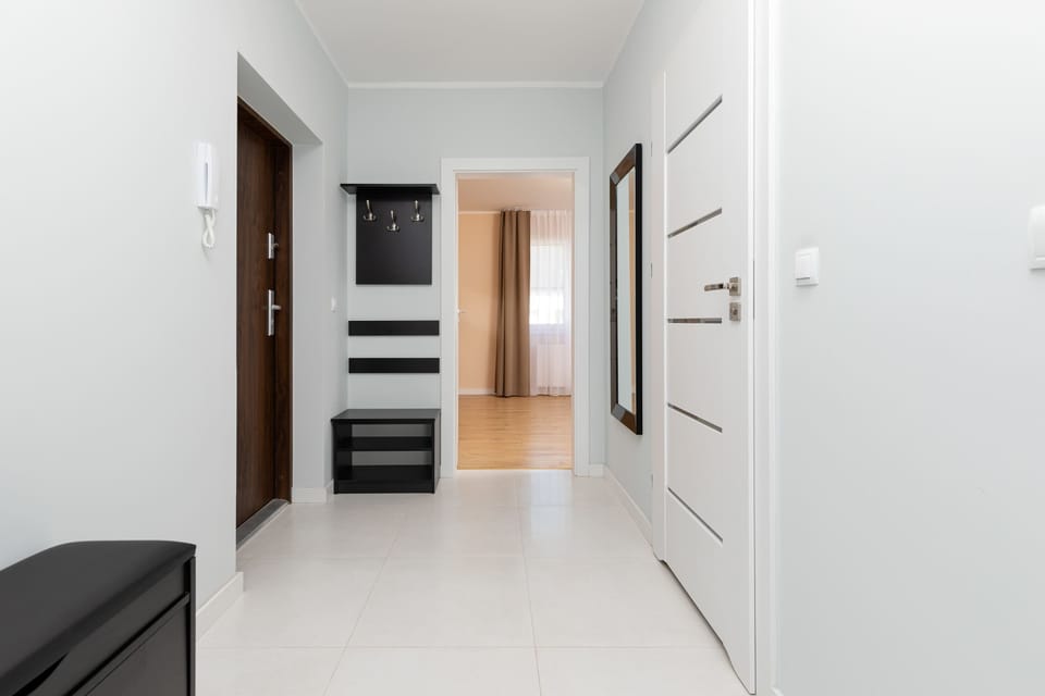 Hallway with  coat racks and doors, leading to different rooms within the apartment.