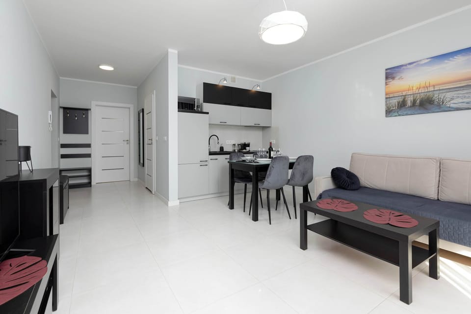 Living room with a sofa bed, TV and fully equipped kitchenette with dining area.