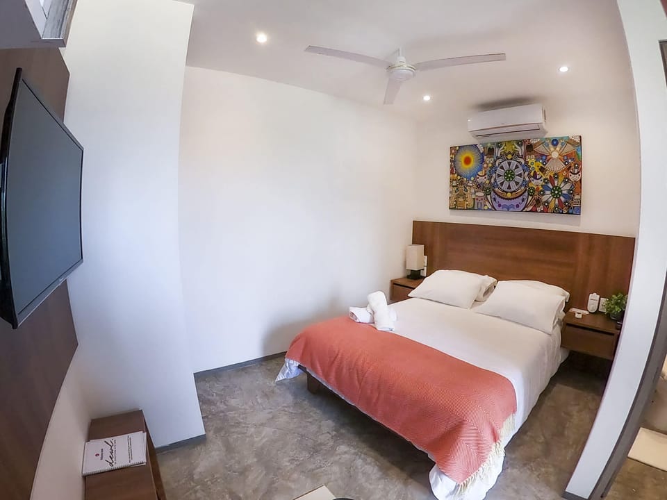 Charming bedroom with a bed and a TV - Discover comfort in Playa del Carmen
