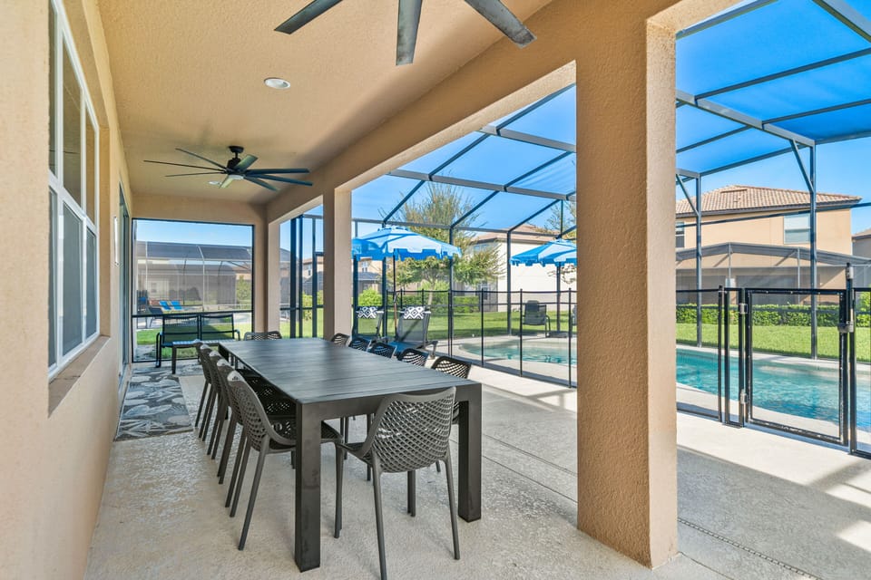 - Covered patio with lounge seating and outdoor dining tables  
- Relax with ceiling fans and poolside access in screened area  
- Orlando villa offering outdoor dining and family gathering