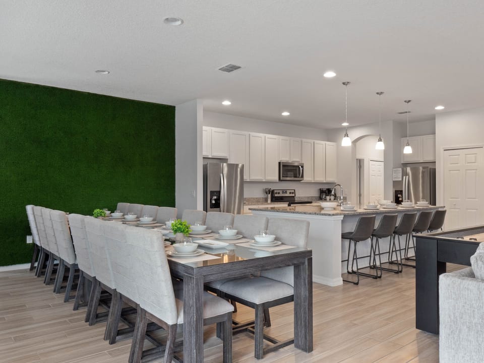 - Spacious dining room with long family table and modern seating  
- Open kitchen with island bar and stainless steel appliances  
- Vacation villa in Orlando perfect for group dining together