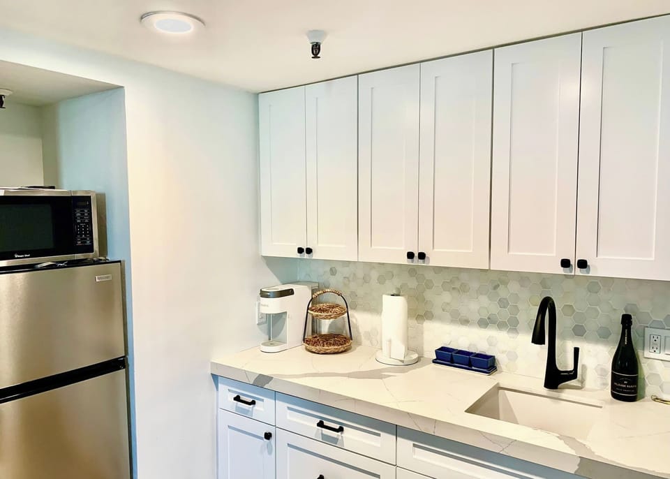 Kitchenette with a Toaster oven, microwave, fridge, Keurig coffee maker, glasses, plates, and cutlery.
