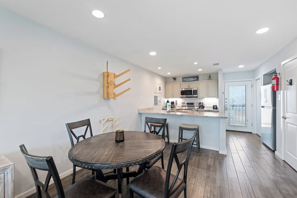 Step into your bright, open-plan dining and kitchen space where gathering for meals feels effortless. The breakfast bar invites leisurely mornings with coffee, while the full kitchen awaits your culinary creativity.