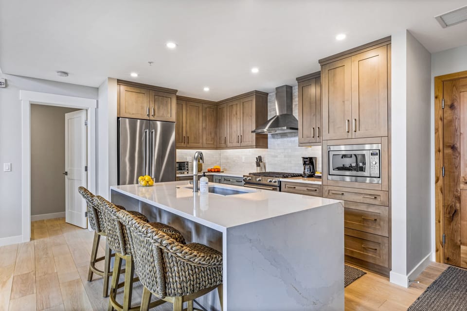 Cook, gather, and entertain in a fully equipped kitchen with a 7’ marble island and 5-burner gas range.
