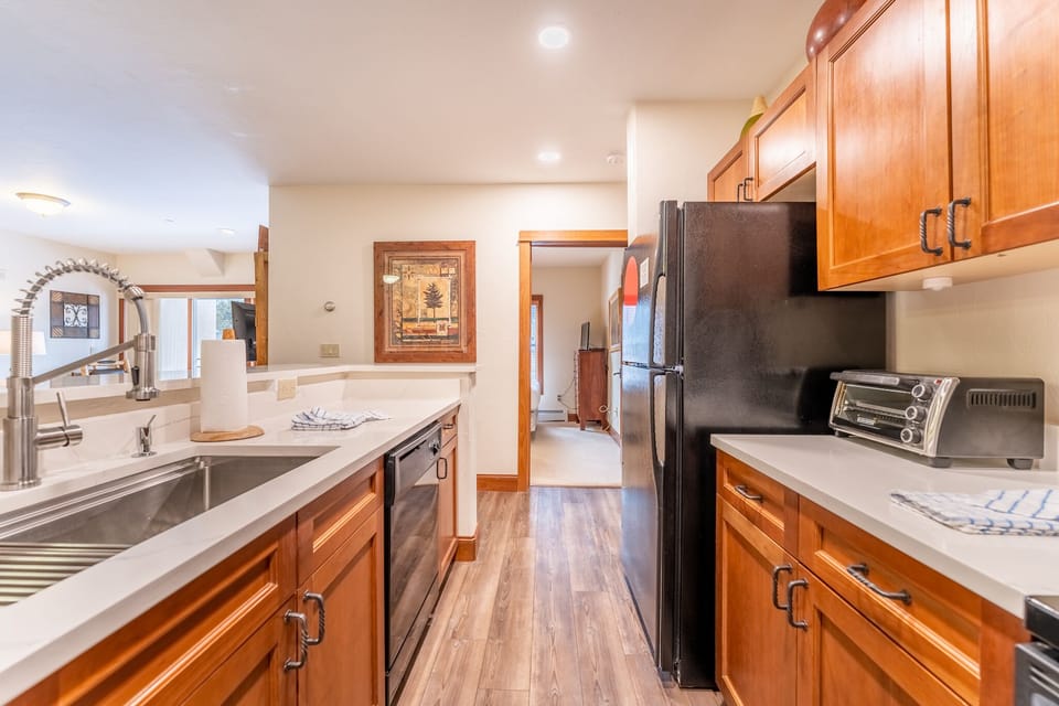 Cook with ease in your spacious kitchen featuring gleaming countertops, modern appliances, and warm wood cabinetry that creates a welcoming culinary haven.