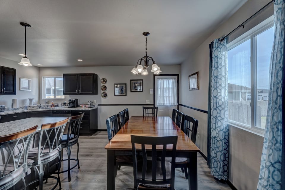 Kitchen with full complement of stainless steel appliances, cookware, bakeware, and large dining room table with seating for 8-10 people. 