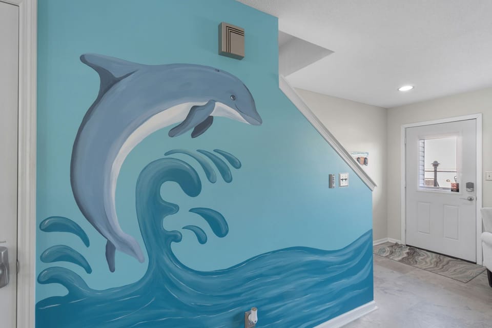 Playful dolphin mural adds a splash of coastal charm to this bright and welcoming entryway