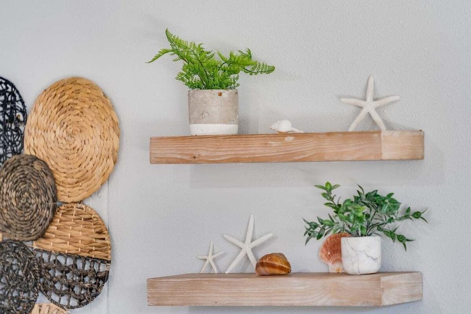 Charming wall shelves with coastal décor and greenery add a fresh, beach‑inspired touch to the space