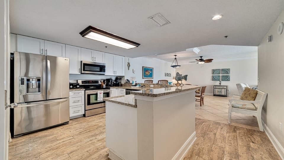 The large island with a breakfast bar provides a central hub for conversation and dining. Whether you're enjoying a quick bite or mingling during a get-together, this area combines comfort and function with style.
