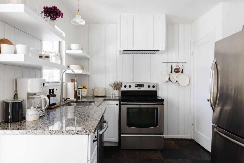 Microwave, utensils, stove, large fridge, dishwasher, pots and pans, and toaster