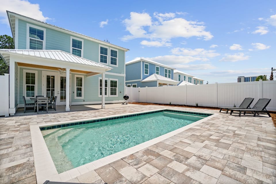 Bright coastal property featuring a private pool area with paver deck and multiple lounge chairs for relaxation.