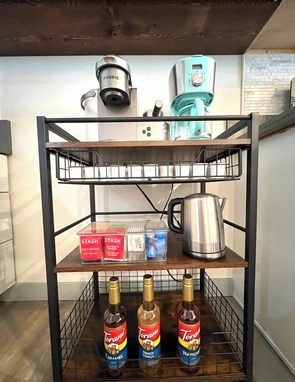 Welcome to our new coffee bar, your personal haven for caffeine delights. Enjoy the convenience of a Keurig coffee maker with a milk frother, a regular drip coffee maker, a selection of teas, and flavored syrups. Indulge in Keurig coffee cups and hot