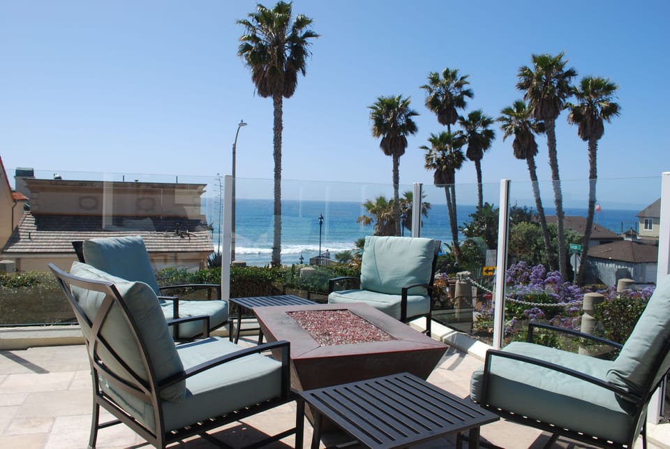 Gas fire pit and comfortable outdoor lounging set look over the Pacific Ocean.