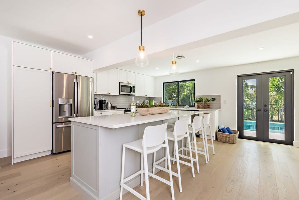 Modern kitchen with a large island and pool access through glass doors