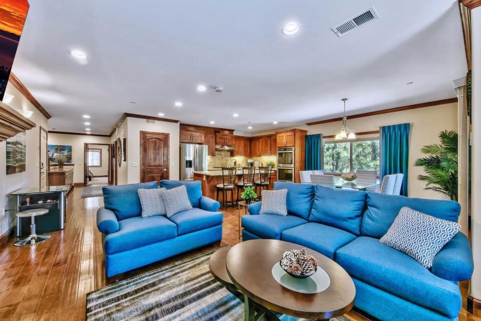Sink into plush blue sofas in your spacious open-plan retreat, where warm wood accents and modern amenities create the perfect gathering space.