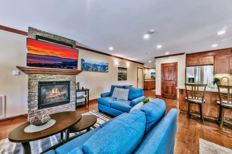 Sink into plush blue sofas by the crackling fireplace, where warm wood accents create the perfect atmosphere for your mountain retreat.