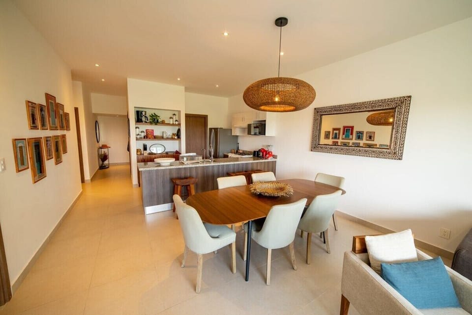 The living room, with an open concept that includes the dining area, the kitchen, the seating and TV area, as well as the balcony overviewing the Tropical garden, the Central Park and the pool.