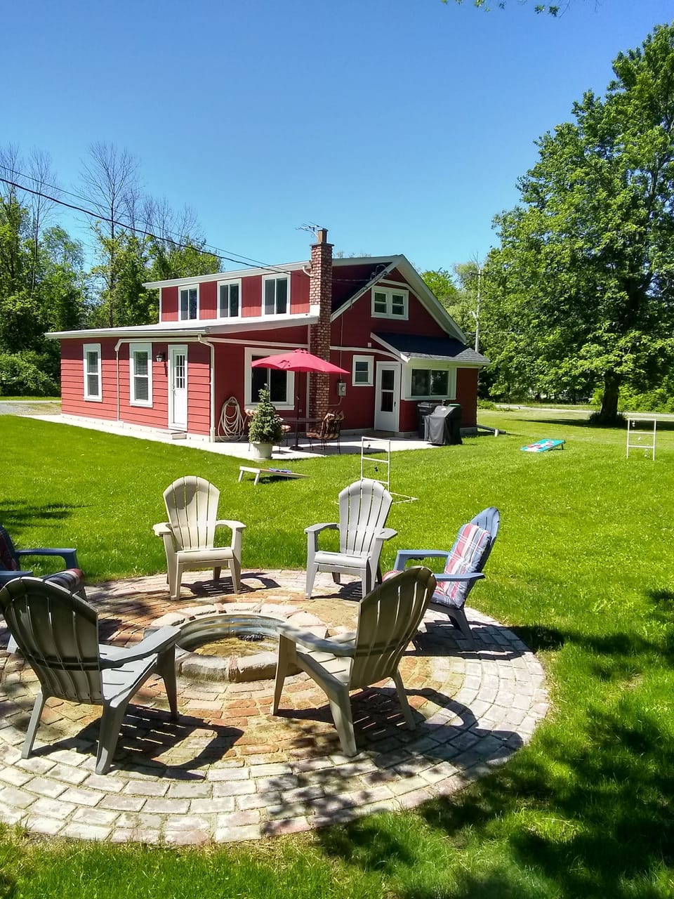 Another view of the firepit with lawn games and house in the background