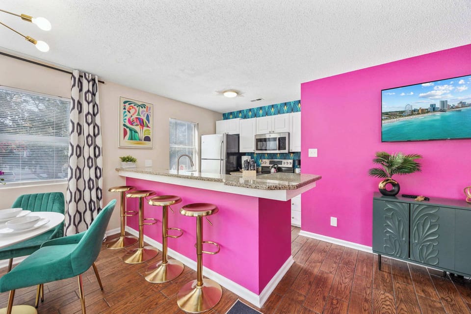 Open kitchen, living room and dining area with smart TV and doors leading to private patio