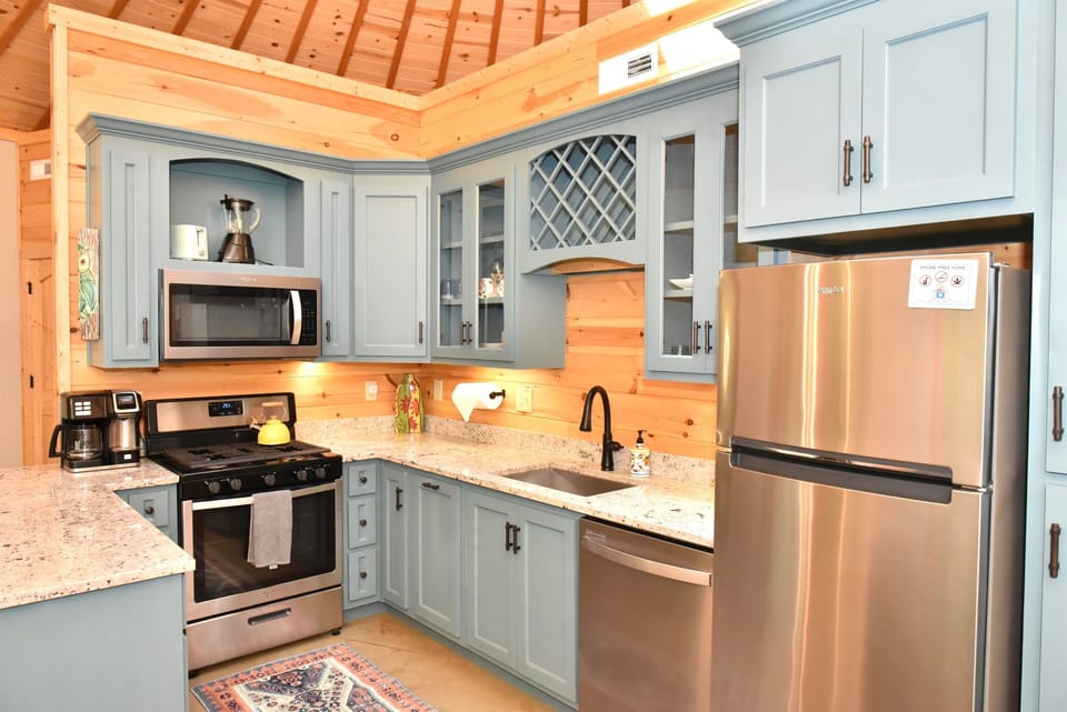 A fully equipped kitchen with soft teal cabinetry, granite counters, and stainless steel appliances — everything you need to cook a real meal and feel right at home in the mountains.