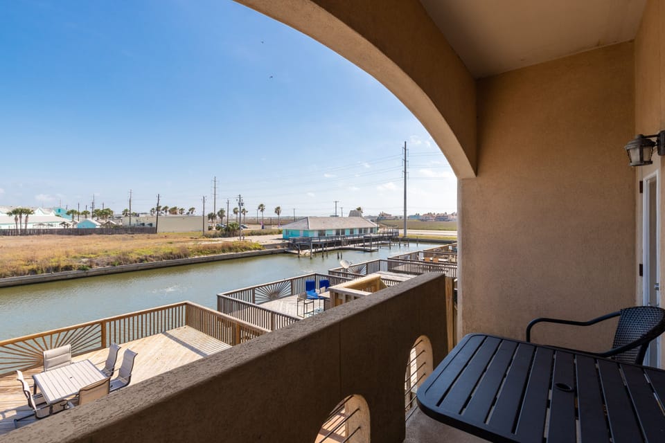 Your private waterfront balcony overlooks a peaceful canal with boat docks, perfect for morning coffee while watching boats glide by.
