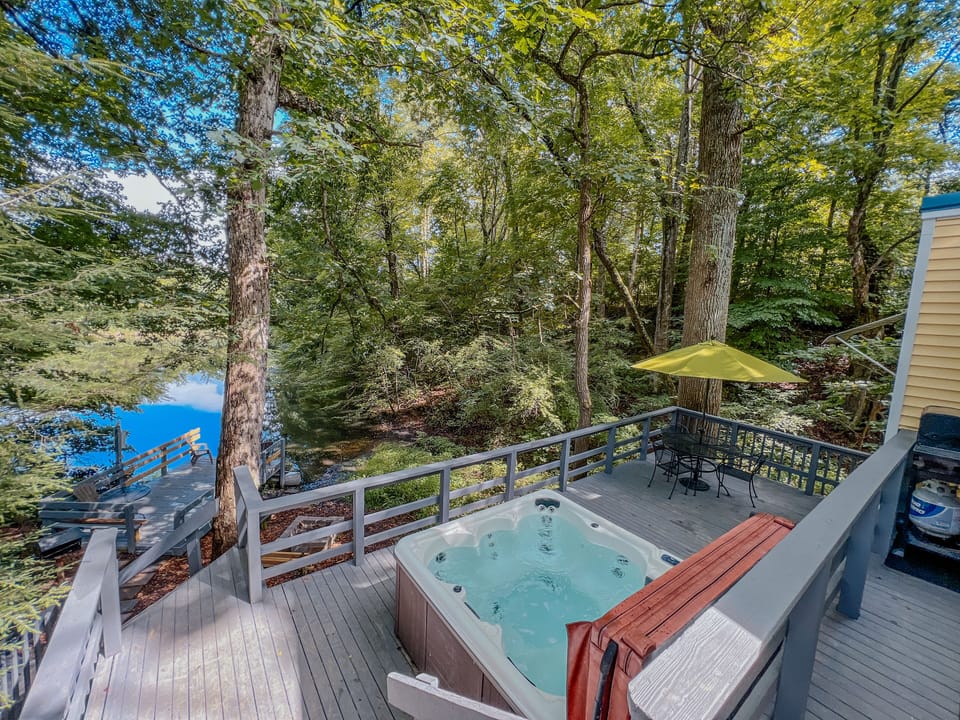 View from the back deck overlooking the hot tub, patio set, and fire pit. 