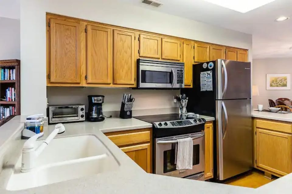 Kitchen has stainless steel appliances and is well stocked to prepare meals.