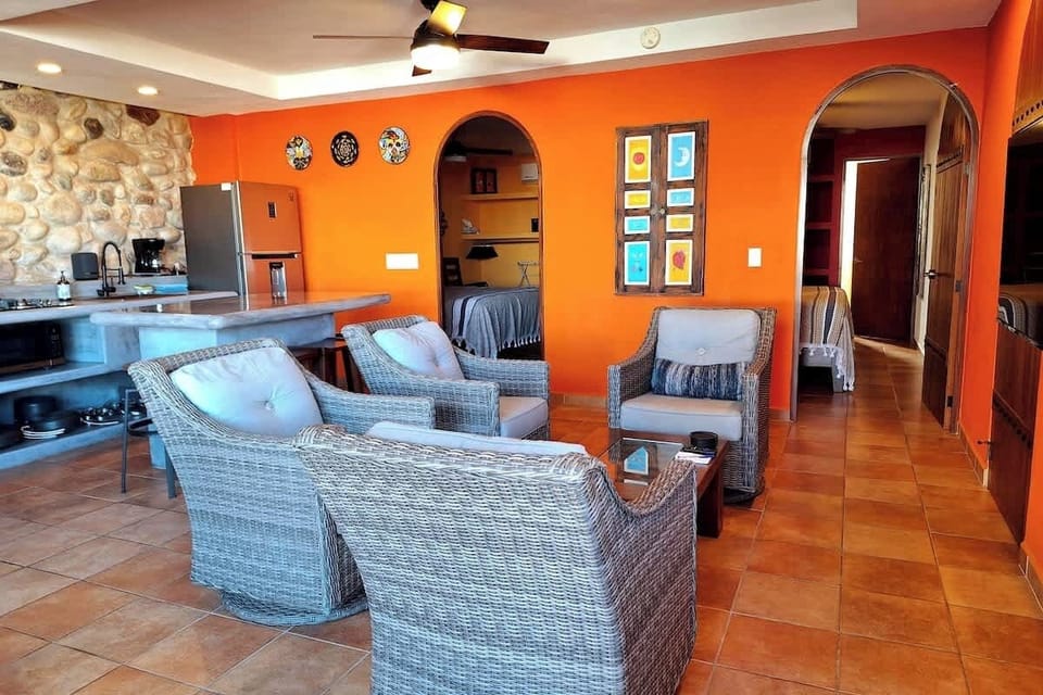 Las Brisas's Living Area with full kitchen, comfortable seating area, and 50 inch Smart TV. Arched doorways lead to the 3 bedrooms each with private en-suite bathrooms. The sliding door opens to allow in the fresh ocean breezes.