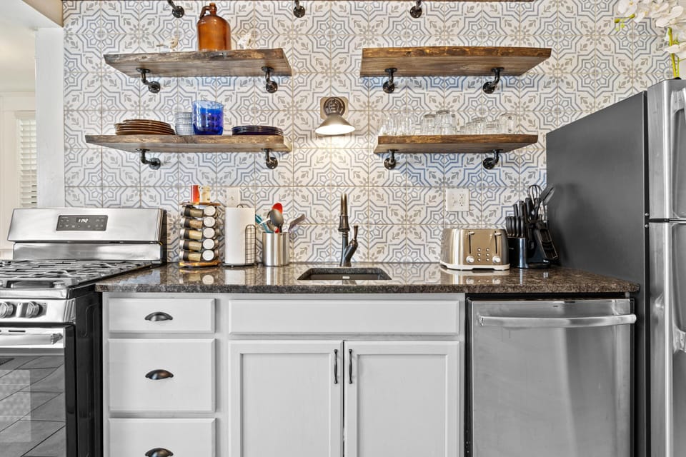 Stylish kitchen featuring open shelving and a stunning patterned backsplash that adds character to the space.