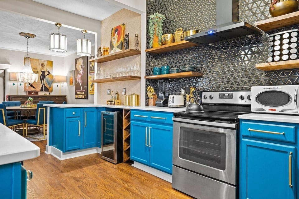 Cook in style in The Luxe’s designer kitchen featuring bold blue cabinetry, floating shelves, gold hardware, and a full suite of modern appliances.