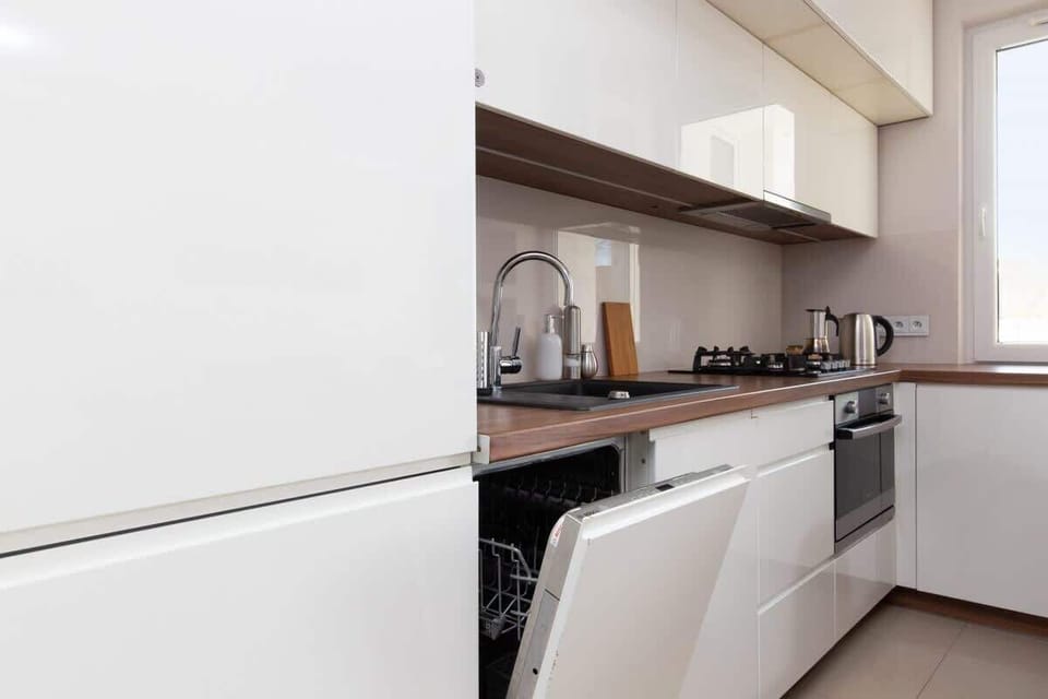 A sleek kitchen area with white cabinets and modern appliances. The layout is functional and integrates well with the rest of the space.
