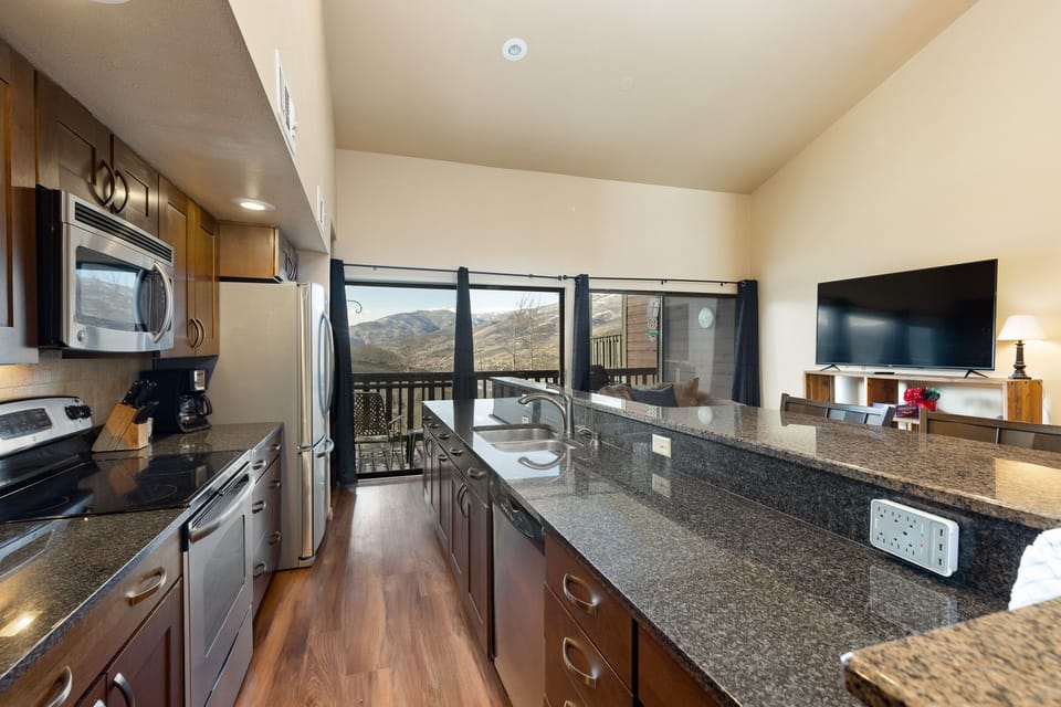 Full size kitchen with granite countertops, stainless steel appliances, hardwood floors and breakfast bar with seating for four.