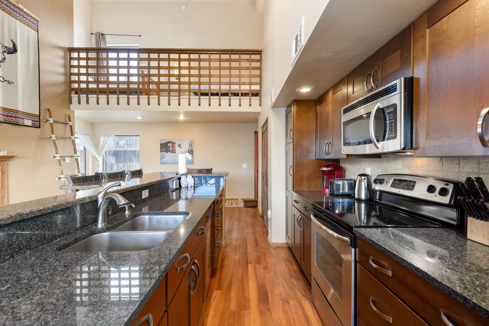 Full size kitchen with granite countertops, stainless steel appliances, hardwood floors and breakfast bar with seating for four.