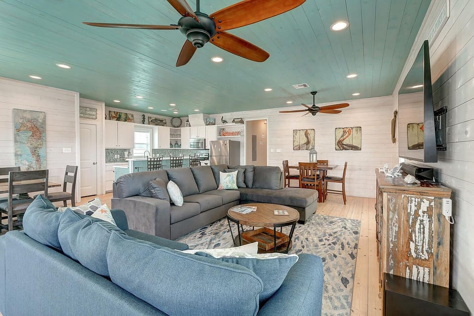 Unwind in this beautifully designed open-concept space where coastal charm meets modern comfort, complete with plush seating and gentle ceiling fans.